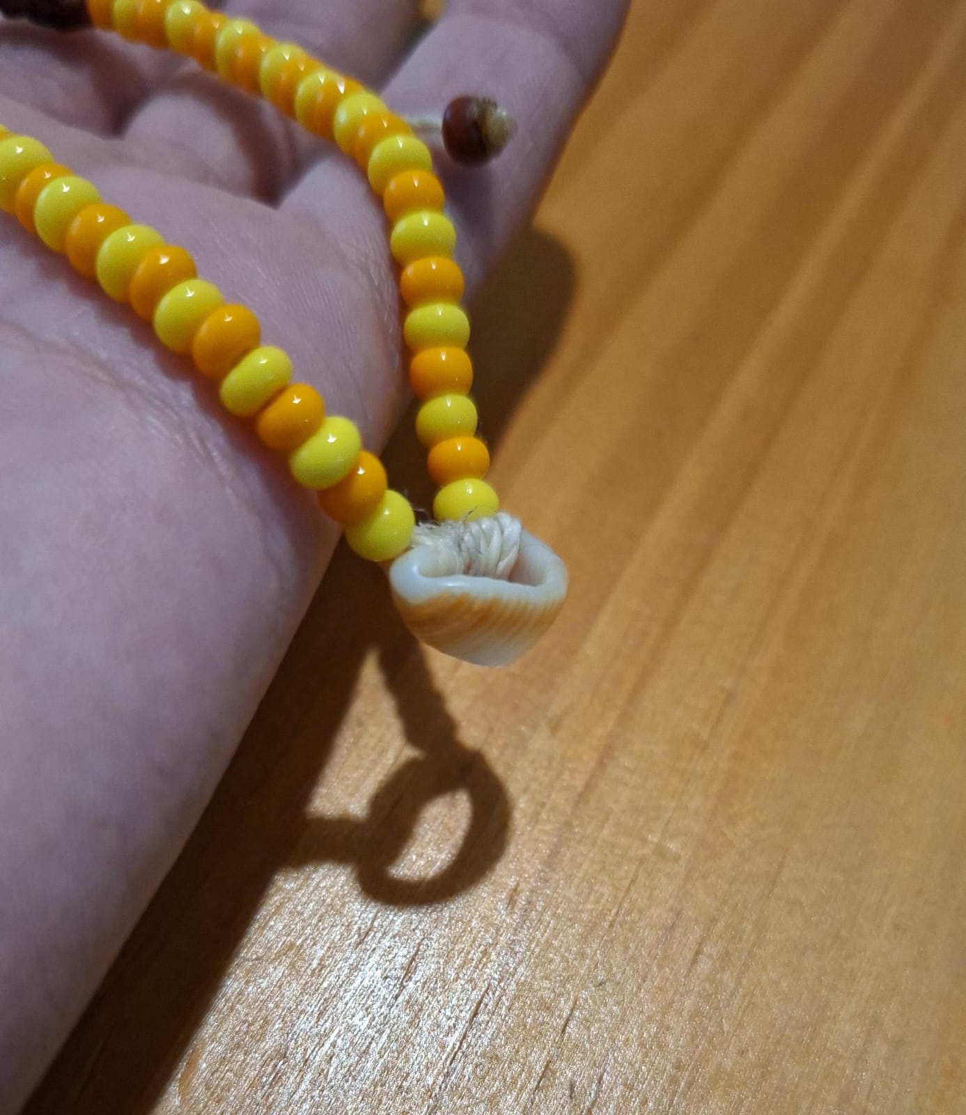 Colar de miçangas amarelas e laranjas com pingente de búzio natural