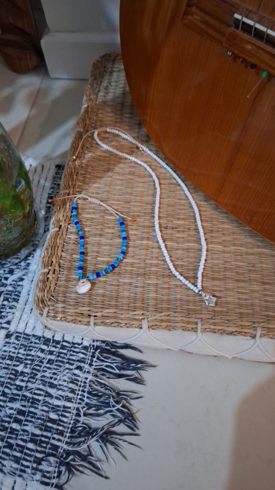 Dois colares de miçangas: um branco com pingente de estrela, outro azul com pingente de búzio