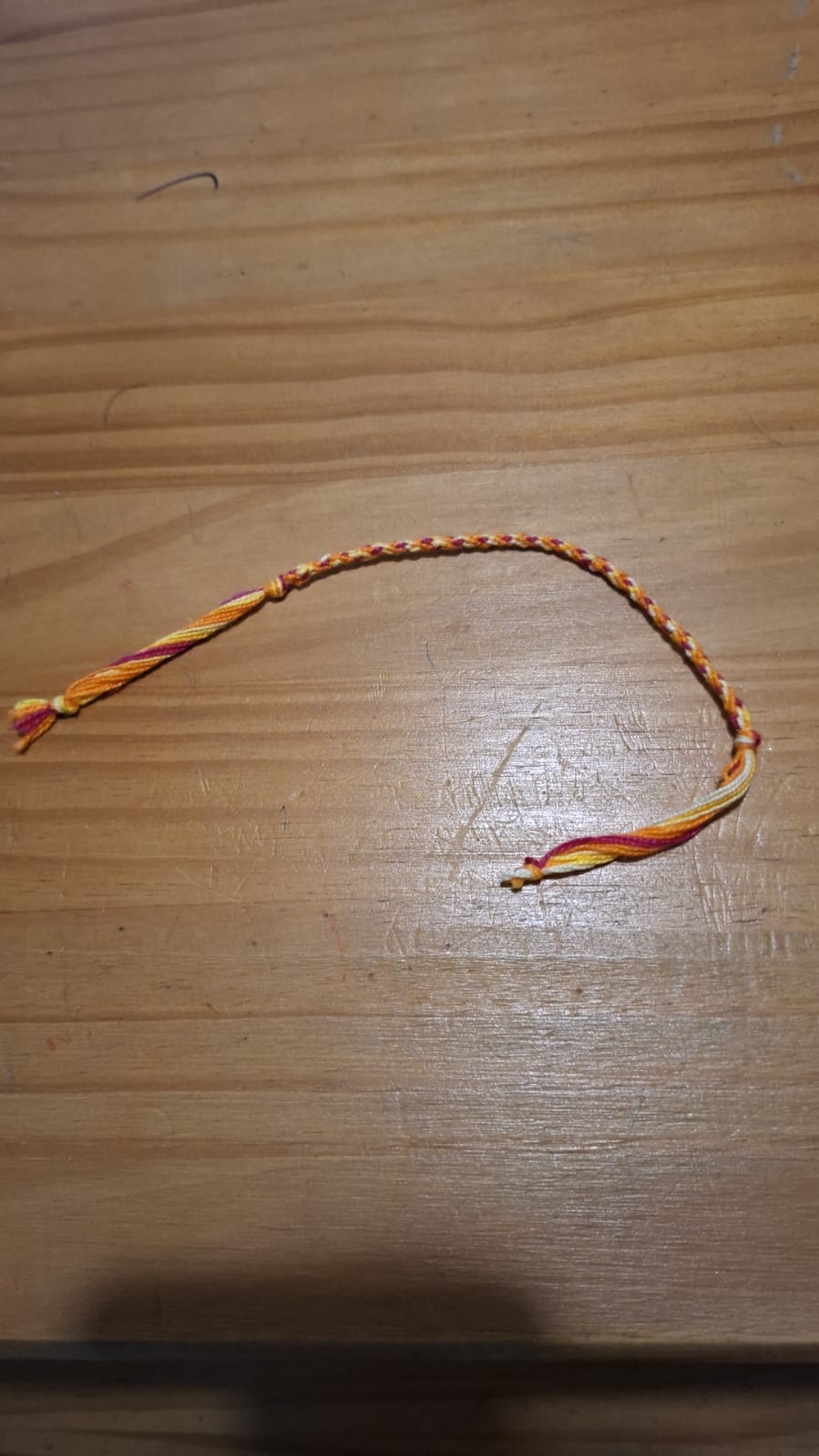 Pulseira trançada em tons quentes de amarelo, laranja e vermelho