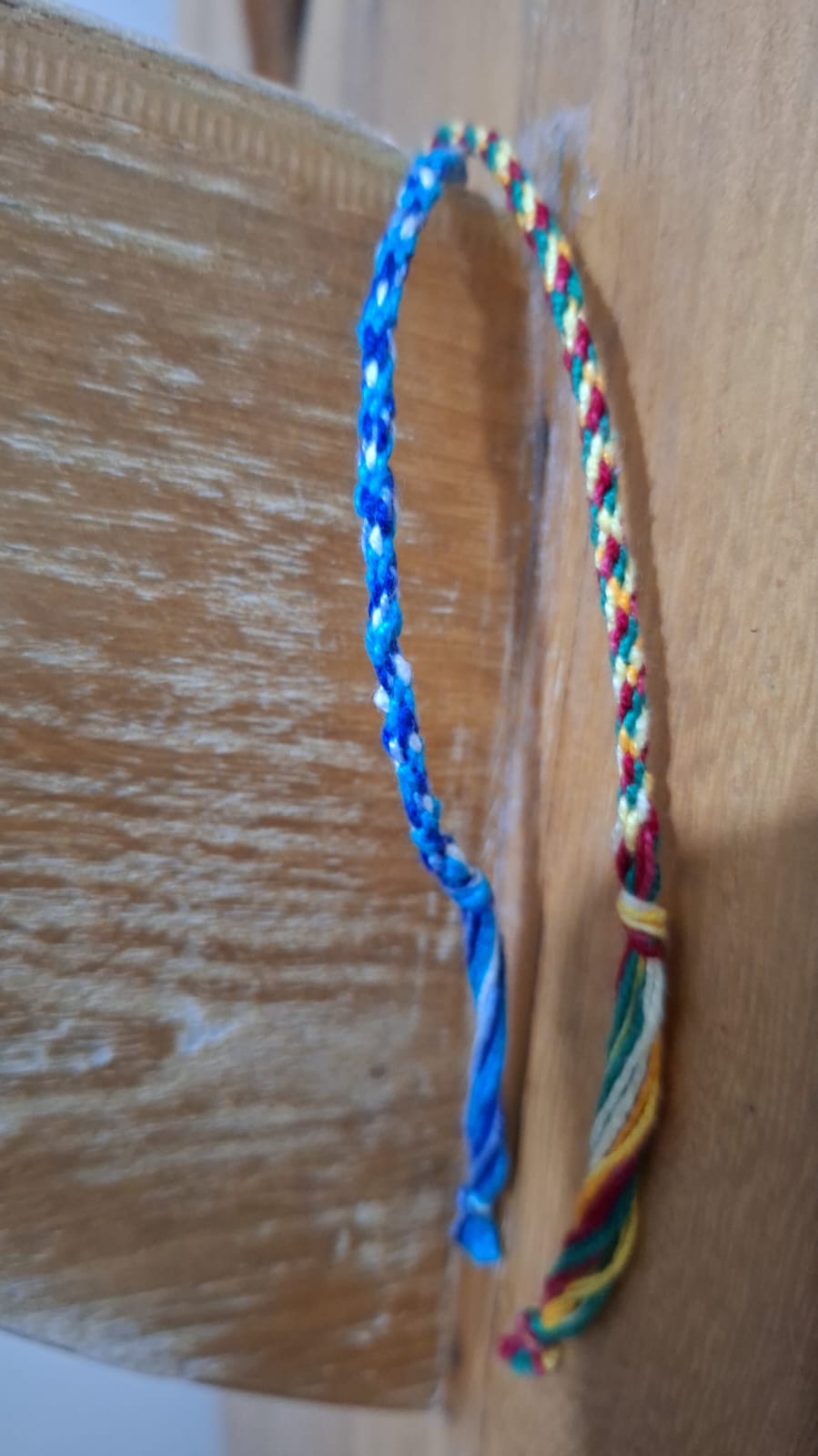 Duas pulseiras trançadas de linha: azul/branca e multicolorida